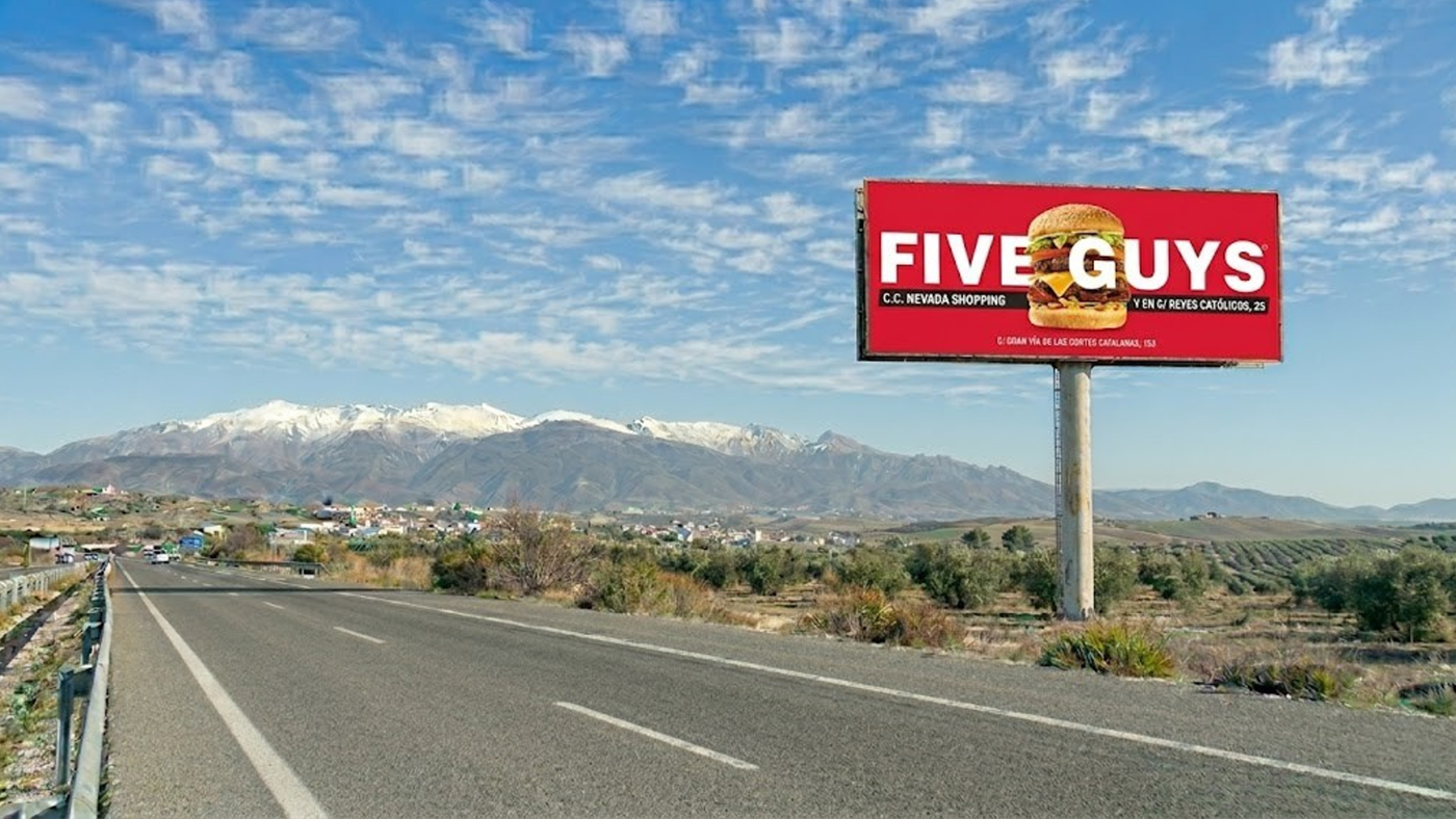 Valla publicitaria en Granada junto a la autovía con Sierra Nevada de fondo